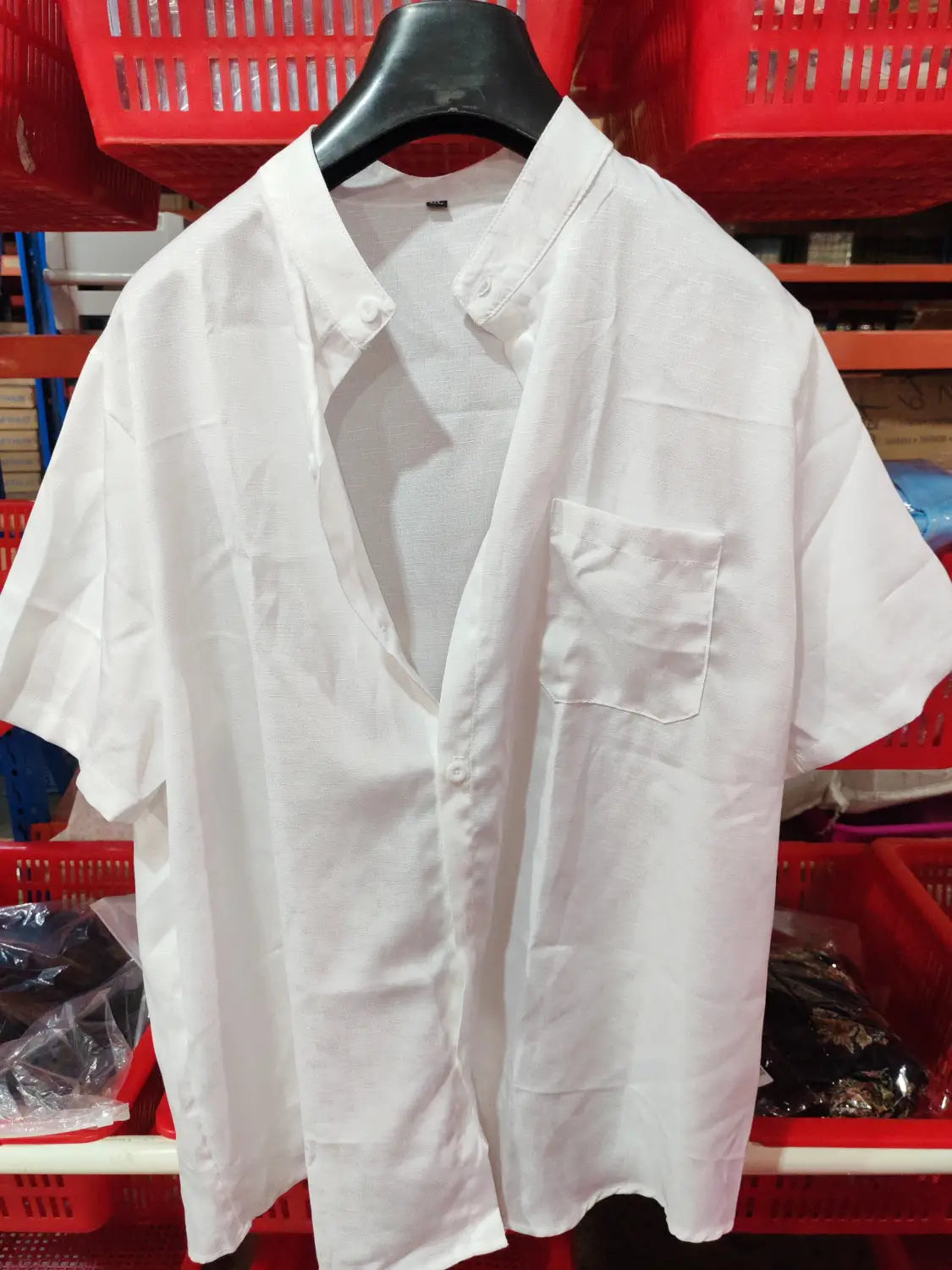 White short-sleeved casual mens shirt with mandarin collar, chest pocket, and button-up front hanging on a black hanger