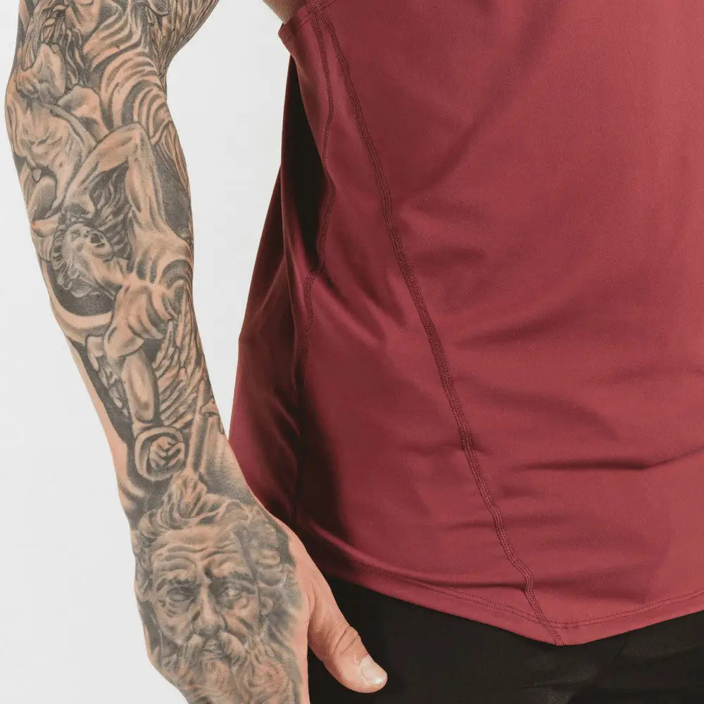 men’s go hard racerback athletic tank top in black showing the back side with a detailed black and gray tattoo featuring intricate mythological figures on the person’s arm