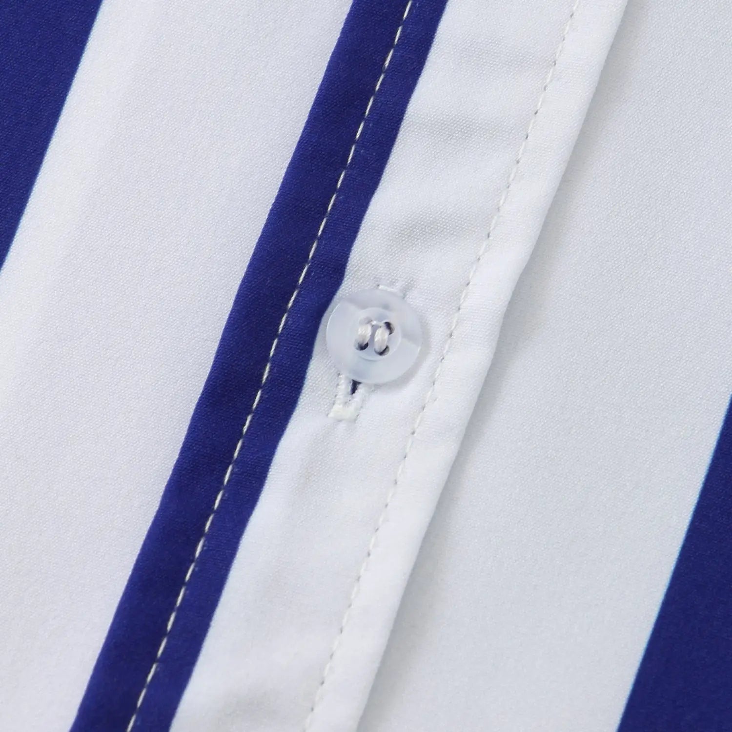 Un bouton en plastique transparent, avec une attache en métal à ton argenté, sur le tissu rayé blanc et bleu marine de la chemise pour homme à rayures, à manches courtes, boutonnée sur le devant.