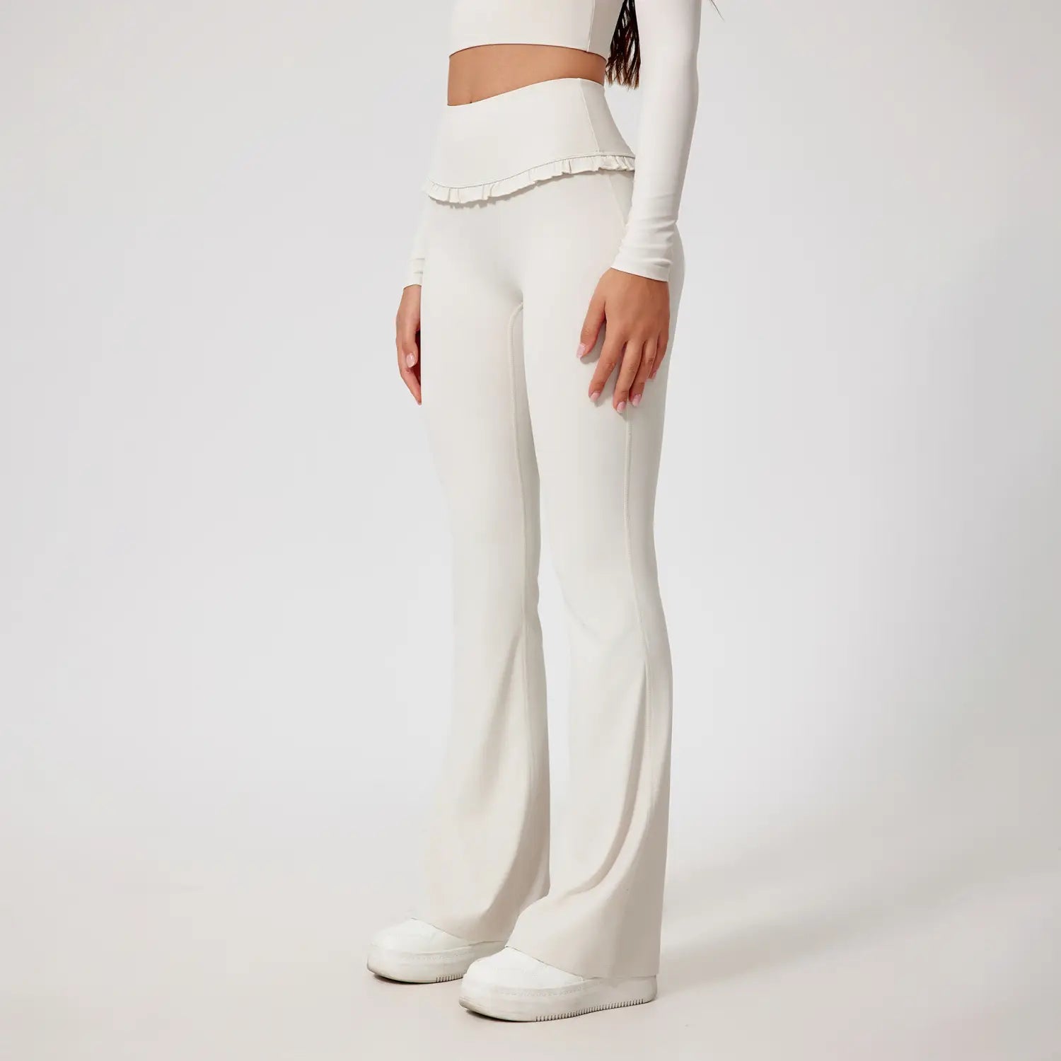 Leggings évasés blancs taille haute avec une taille à volants, conçus comme pantalons pour activités.