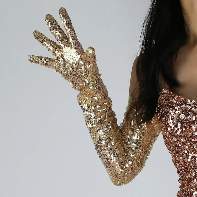 A shimmering gold sequined mesh finger glove with a sparkling glittery texture and long elegant design shown from the back side.