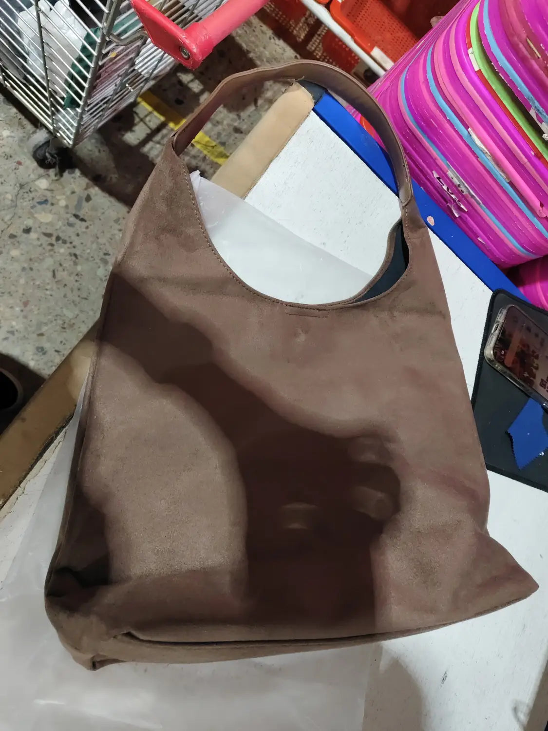 A taupe suede shoulder bag with a large capacity slouchy tote design featuring a single top handle and an open front.