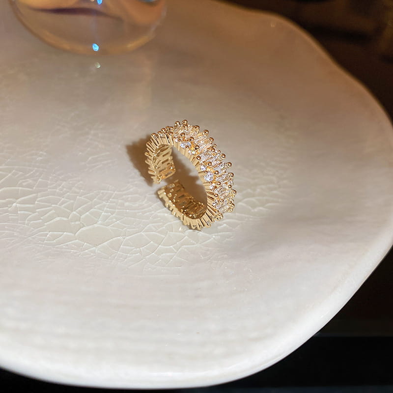 Gold-toned adjustable hollowed square pearl and baguette zircon open ring adorned with a row of clear faceted crystals set in an intricate textured band.