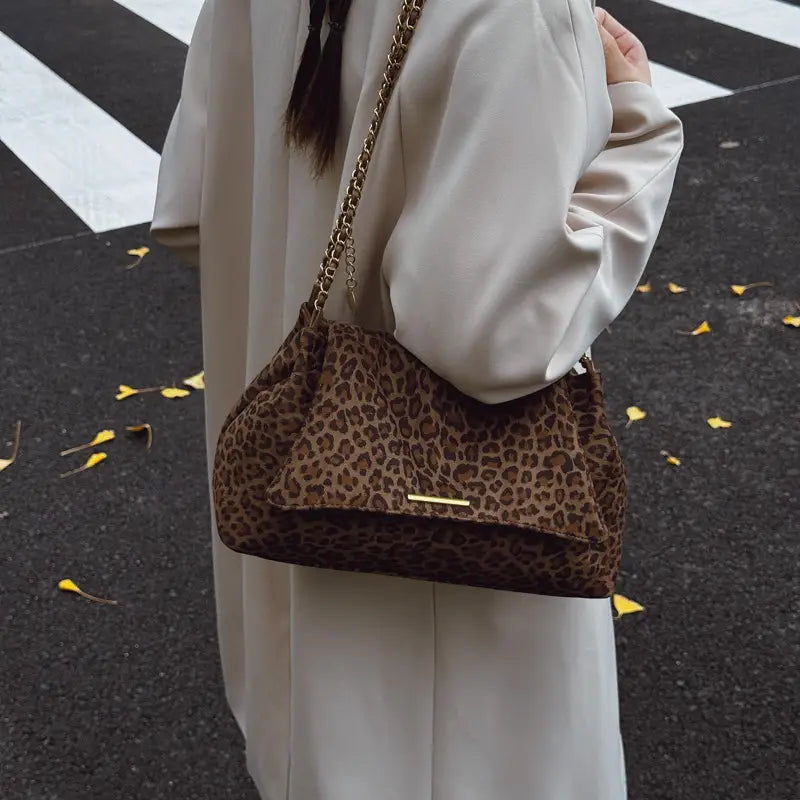 leopard print crossbody bag in brown with a gold chain strap and matching metallic clasp shown from the front.
