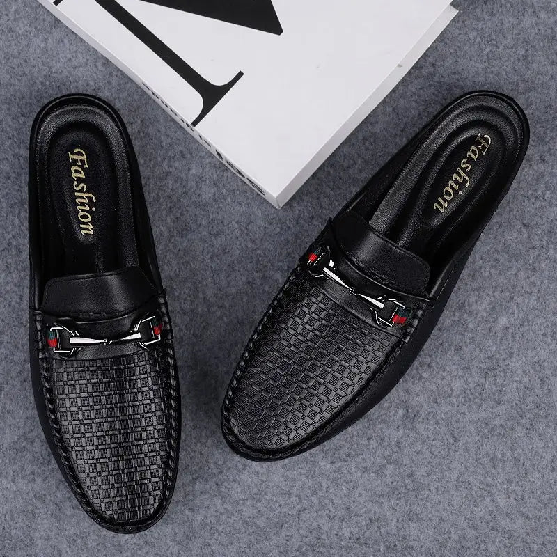 Men’s black leather mule loafers with woven texture and silver-toned metal buckles accented by red details.