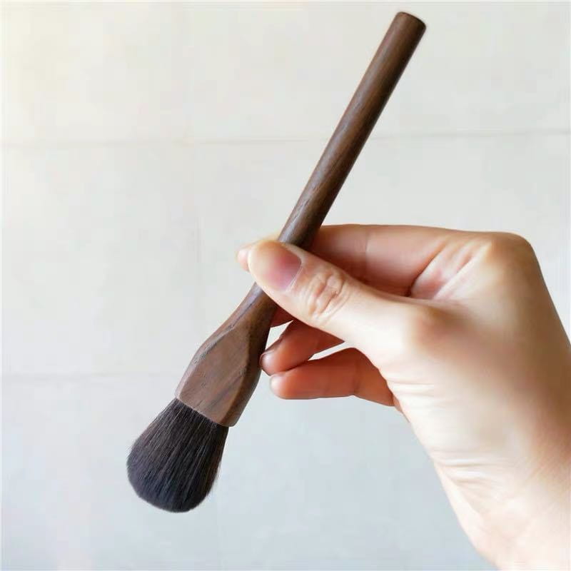 A sleek dark brown walnut wood handled makeup brush with soft black fiber bristles from the Walnut Wood Makeup Brush Set.