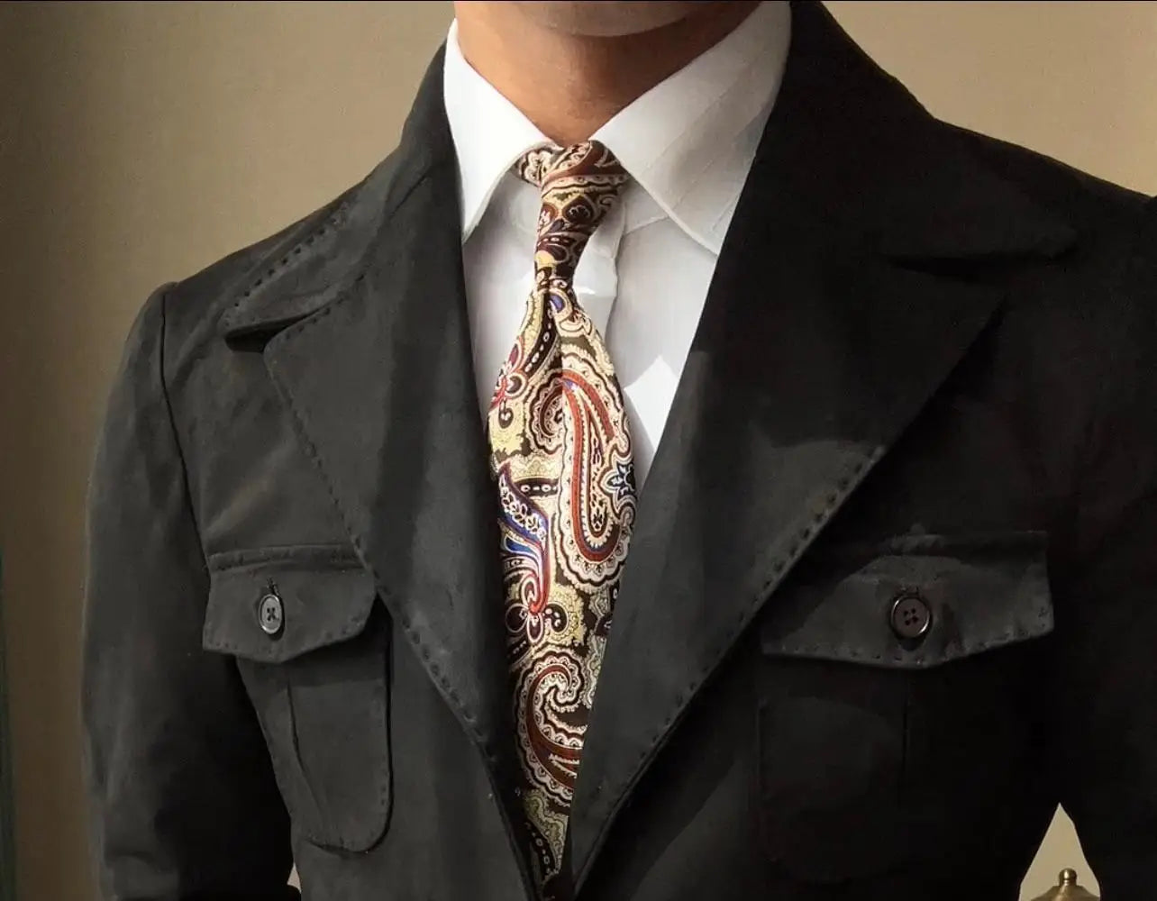 un abrigo de terciopelo de ante para hombre en verde oliva retro de primavera, combinado con una corbata tipo paisley de patrón elaborado en tonos de marrón, rojo y dorado