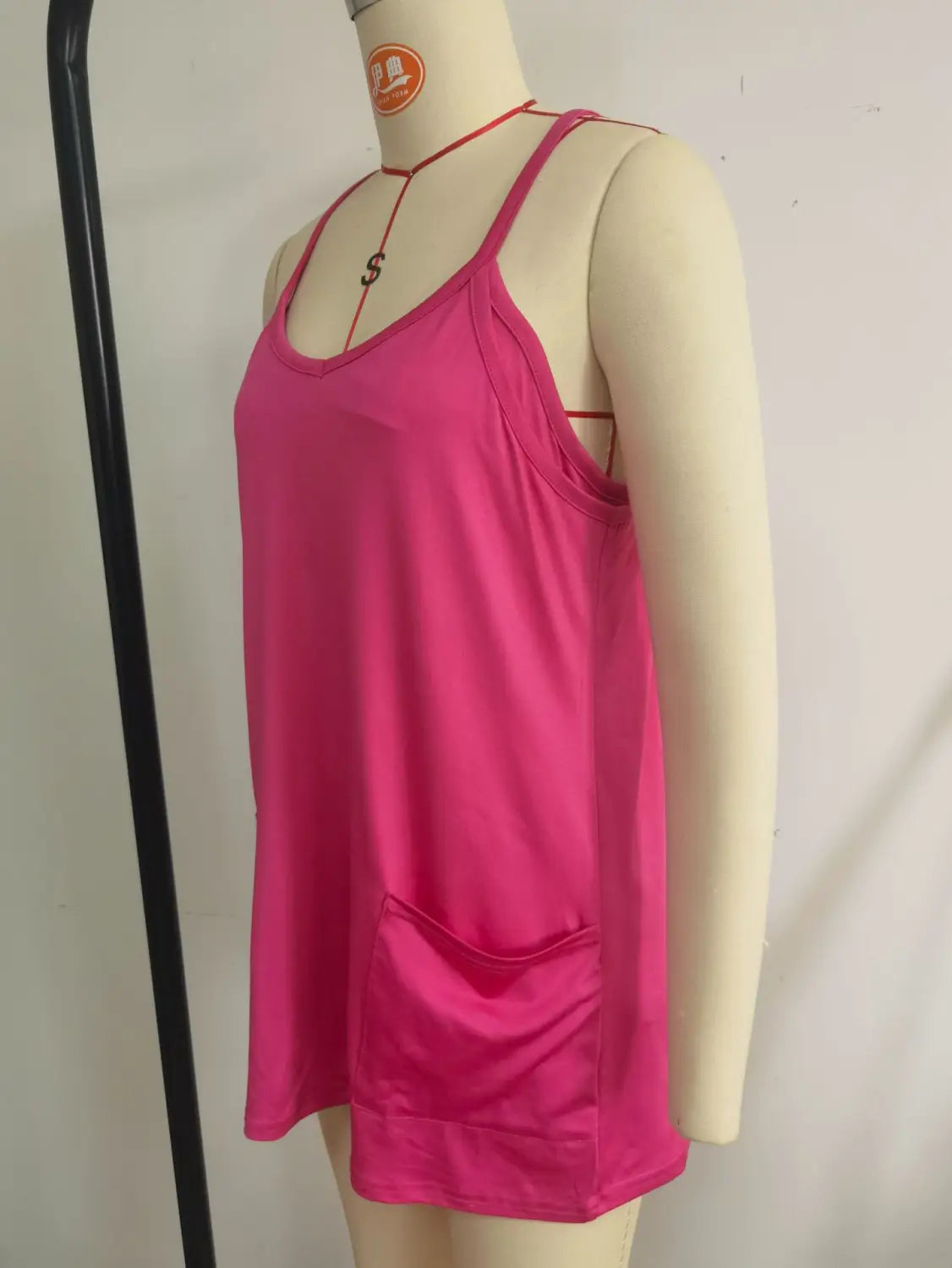 A vibrant pink satin tank top with thin straps and a front pocket featured in a women casual romper and strap top set.