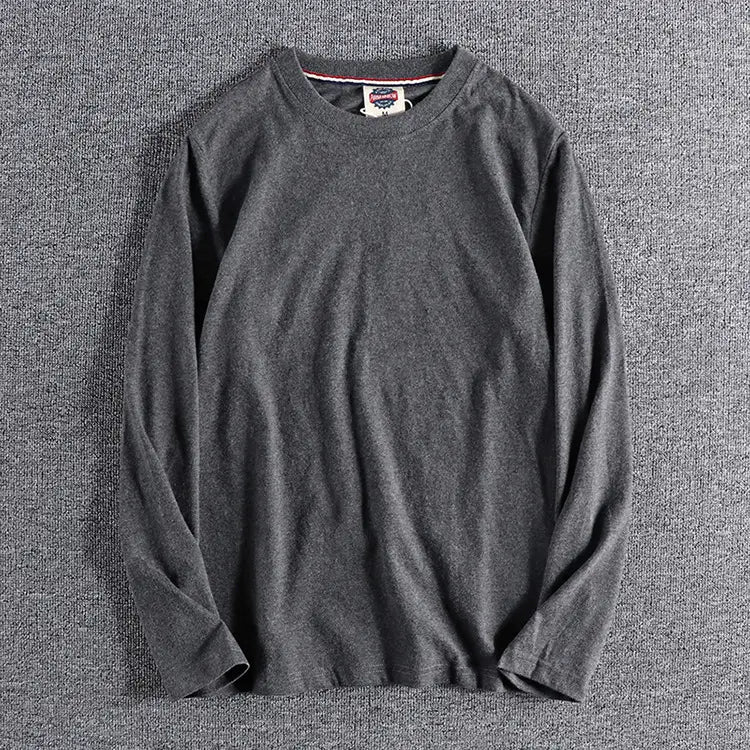 Camiseta de color liso lavado gris oscuro de manga larga con una tela suave ligeramente texturizada y puños acanalados discretos.