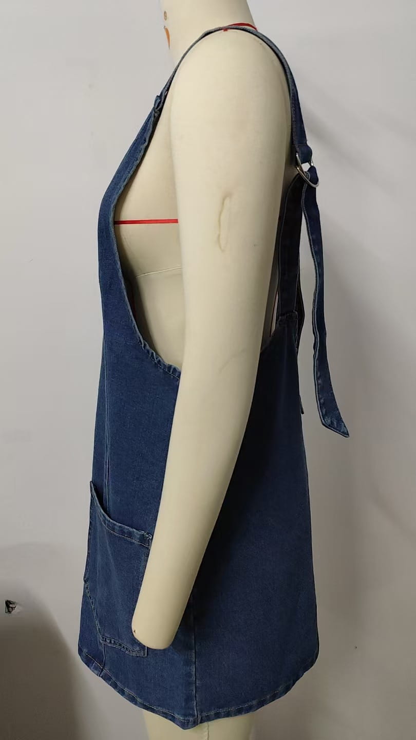 Vestido peto de mezclilla azul de longitud media con ribete de encaje que presenta tirantes ajustables y bolsillos delanteros en un material de mezclilla resistente.