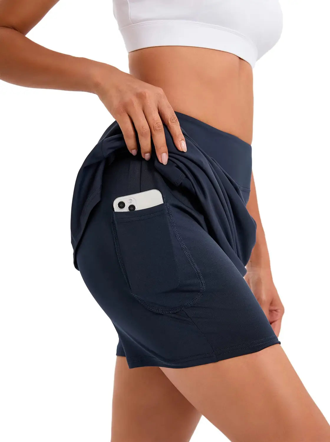Navy blue paisley high-waisted athletic tennis skirt made of breathable material with a side pocket holding a smartphone.