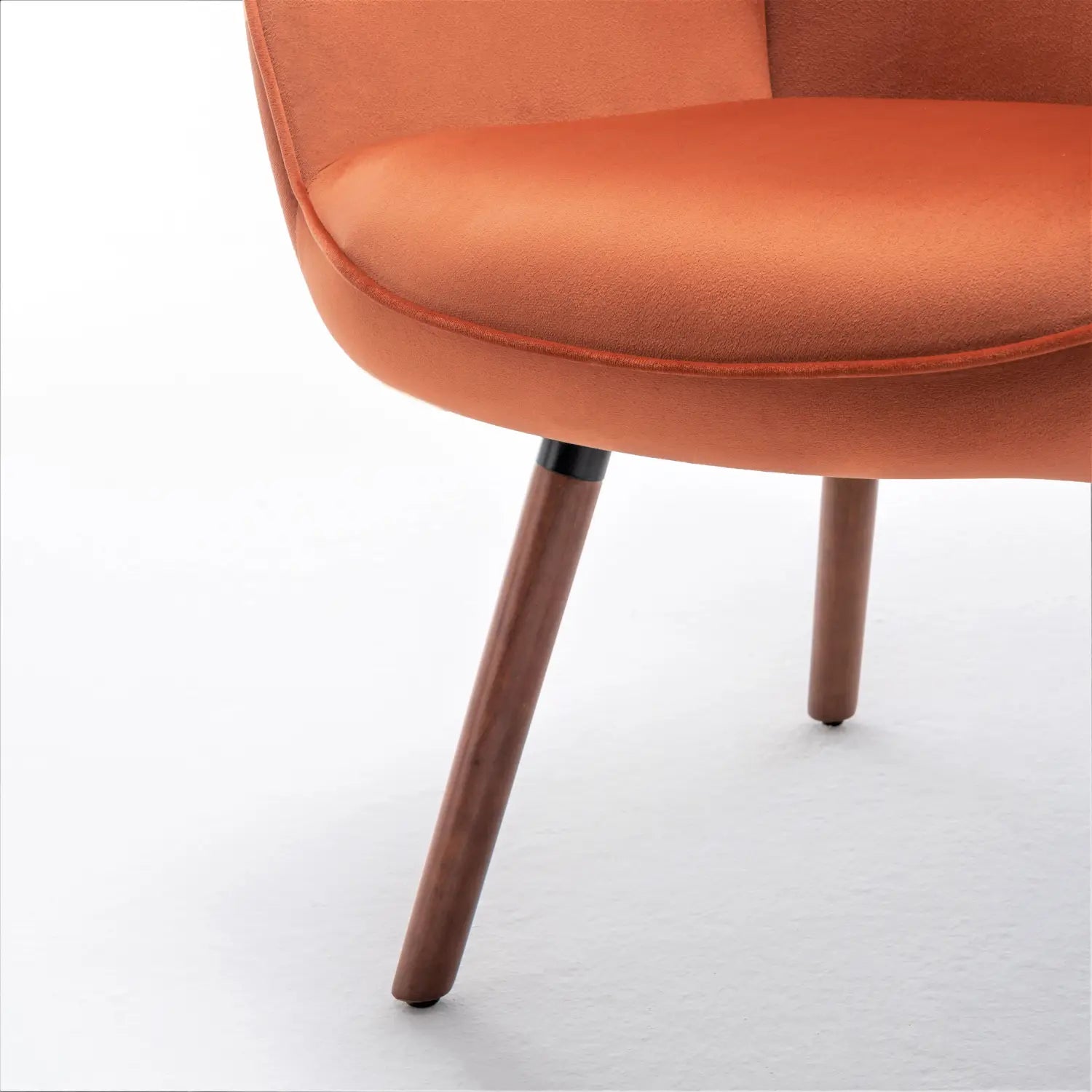 Una silla de acento tipo wingback de estilo moderno de mediados de siglo en naranja, con un tapizado de terciopelo acogedor y patas de madera elegantes.