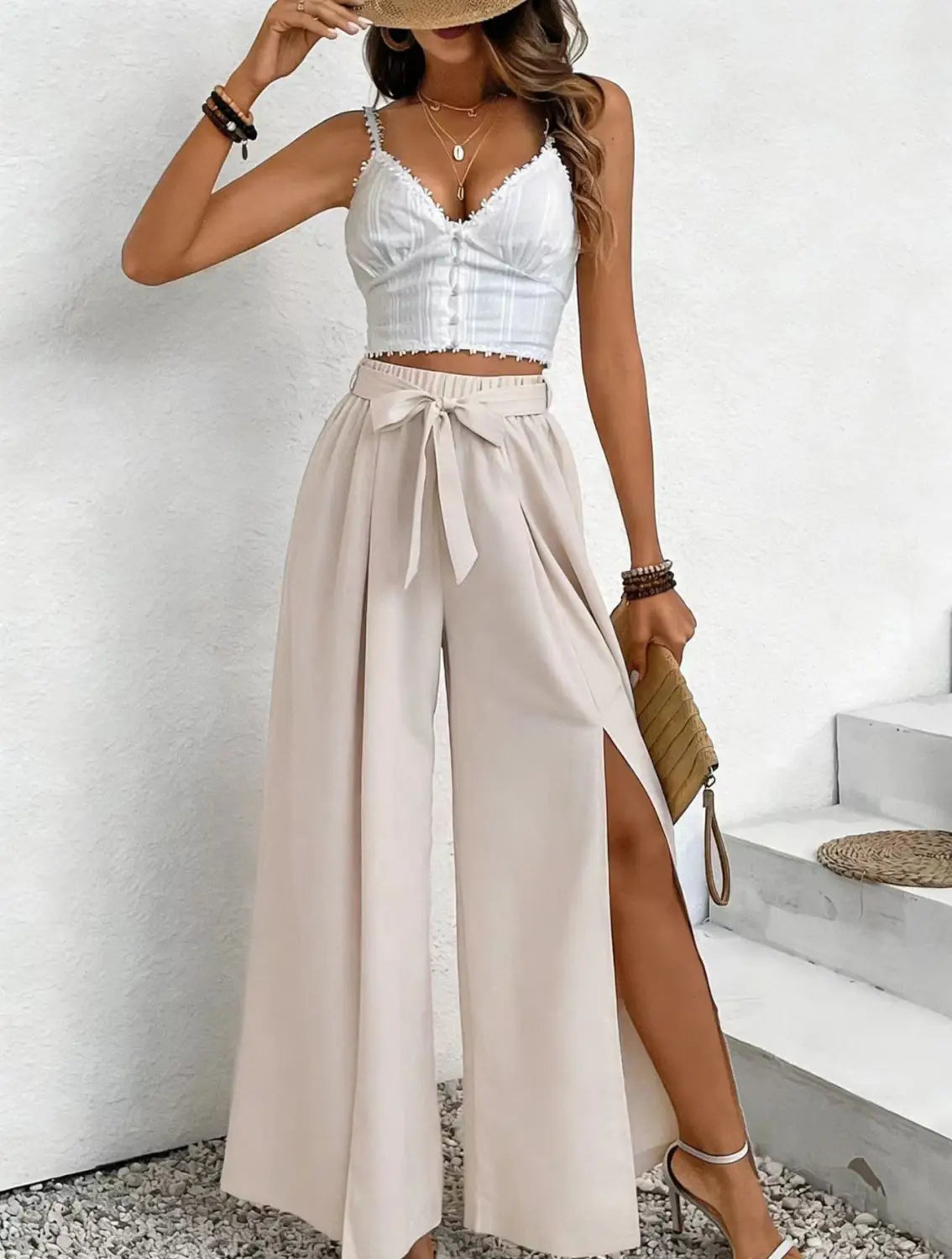 Pantalon ample à taille haute beige fabriqué dans un tissu ample décontracté, avec une ceinture nouée et une fente latérale.