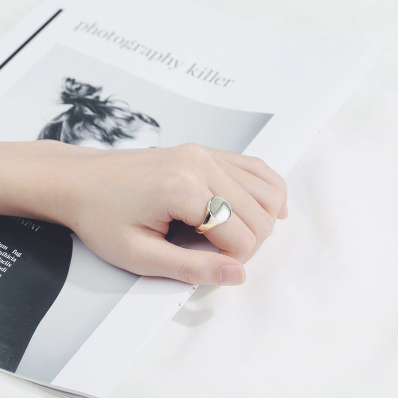 An adjustable oval minimalist signet ring in polished silver metal featuring a sleek smooth polished oval face and a simple band.