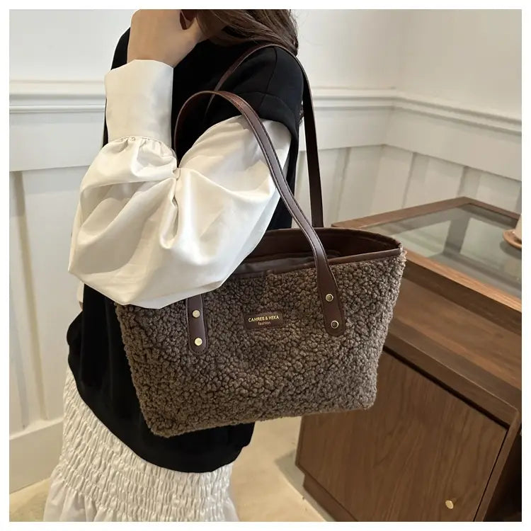 brown faux fur tote bag with leather straps featuring a brown fuzzy texture and a metallic logo plaque on the front