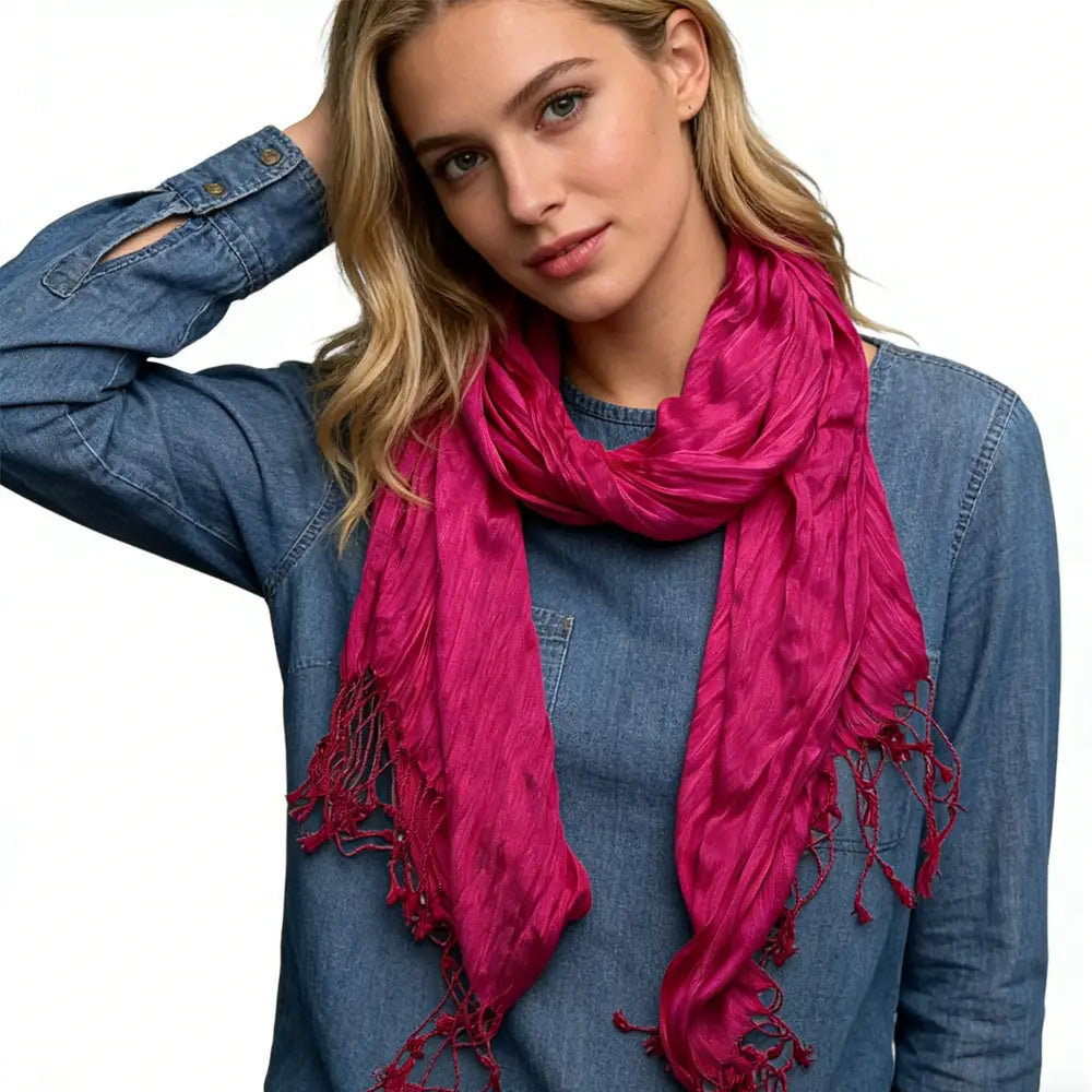 Écharpe rose fuchsia froissée éclatante, avec un tissu légèrement froissé et texturé ainsi que des bords effilochés, conçue comme accessoire de femme.
