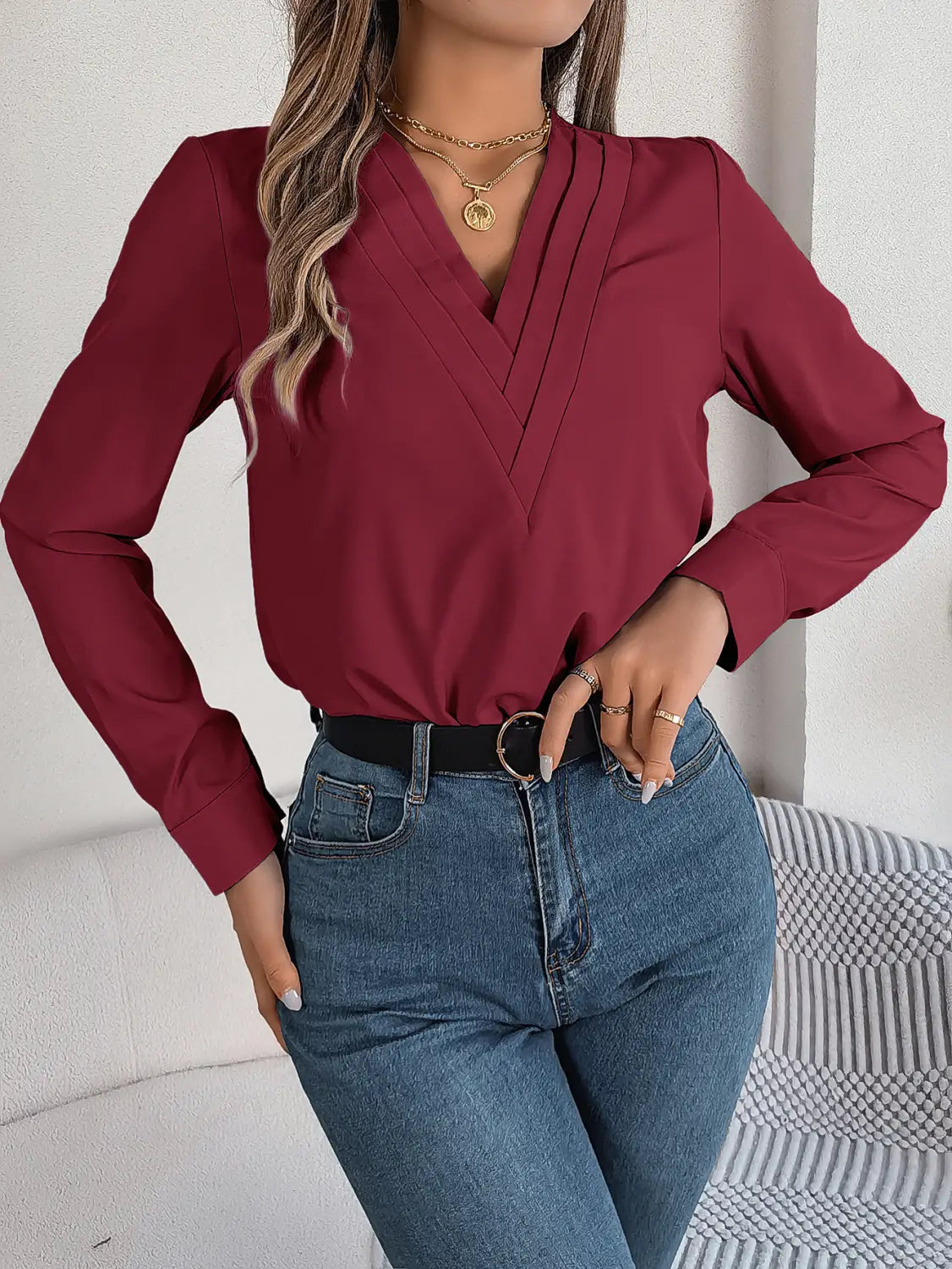 A maroon long-sleeved blouse with a v-neck and pleated detailing combined with white satin wrap blouse featuring black trim.