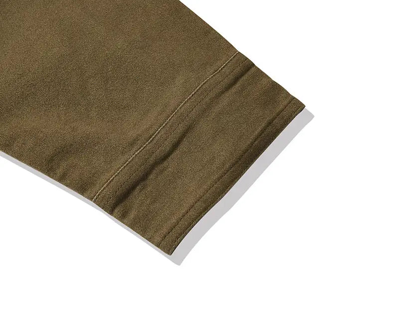 Olive green cotton sleeve with a neatly stitched hem on a mens French workwear jacket cotton utility pocket coat.