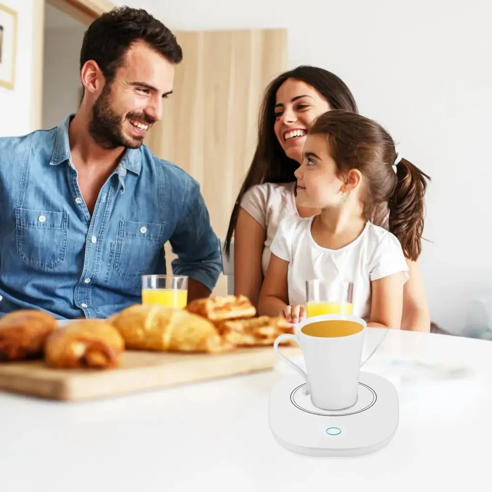 White ceramic mug resting on a sleek white smart electric coffee mug warmer with auto shut and blue indicator light