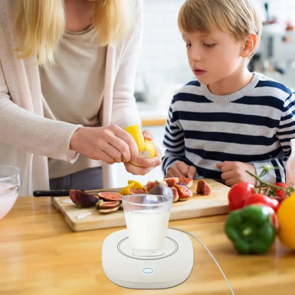 White circular electric coffee mug warmer with auto shut and glowing blue indicator light for desk use