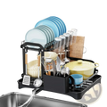 Black metal 2-tier dish drying rack with automatic drainage system holding blue and white plates glasses and utensils
