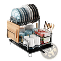 Black metal 2-tier dish drying rack with wooden drainboard holding assorted dishes cups utensils and food containers