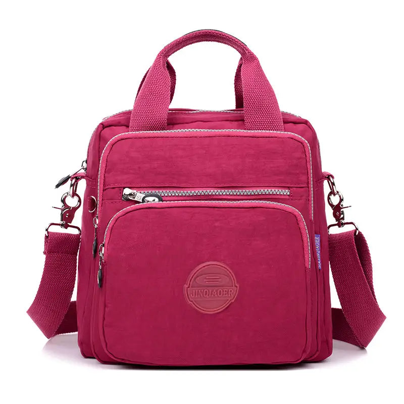 A vibrant magenta nylon messenger bag with a top handle adjustable shoulder strap and multiple zippered compartments designed as a multi zipper canvas backpack.