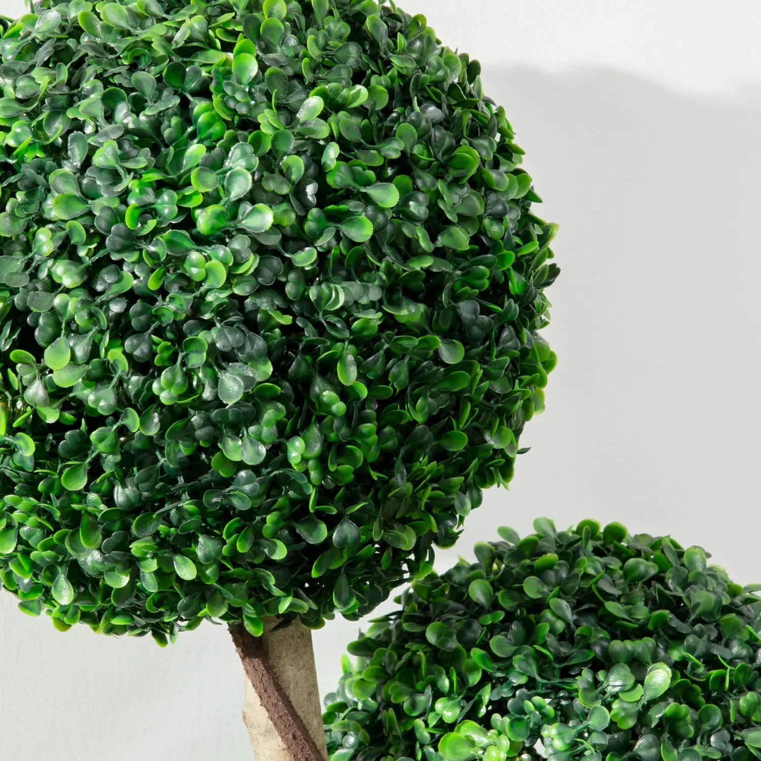 Un árbol topiario artificial de boj frondoso y esférico, con follaje verde vibrante y denso y un tronco marrón con textura, en un conjunto de dos, con una medida de 35,5 pulgadas.