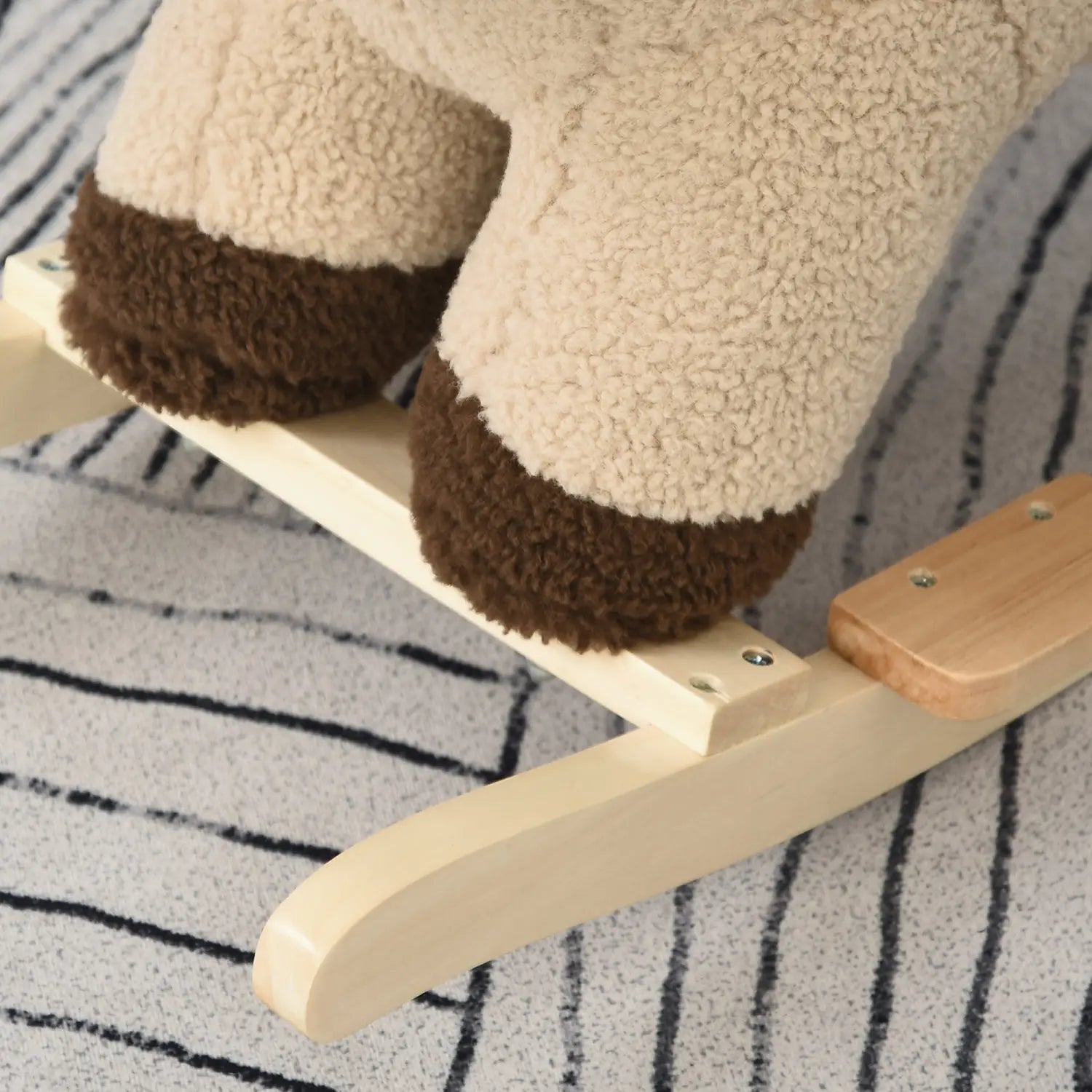 Cheval à bascule en peluche de couleur crème en forme de lion avec fonction sonore, accents de sabots bruns, harnais de sécurité et base en bois pour le basculement.