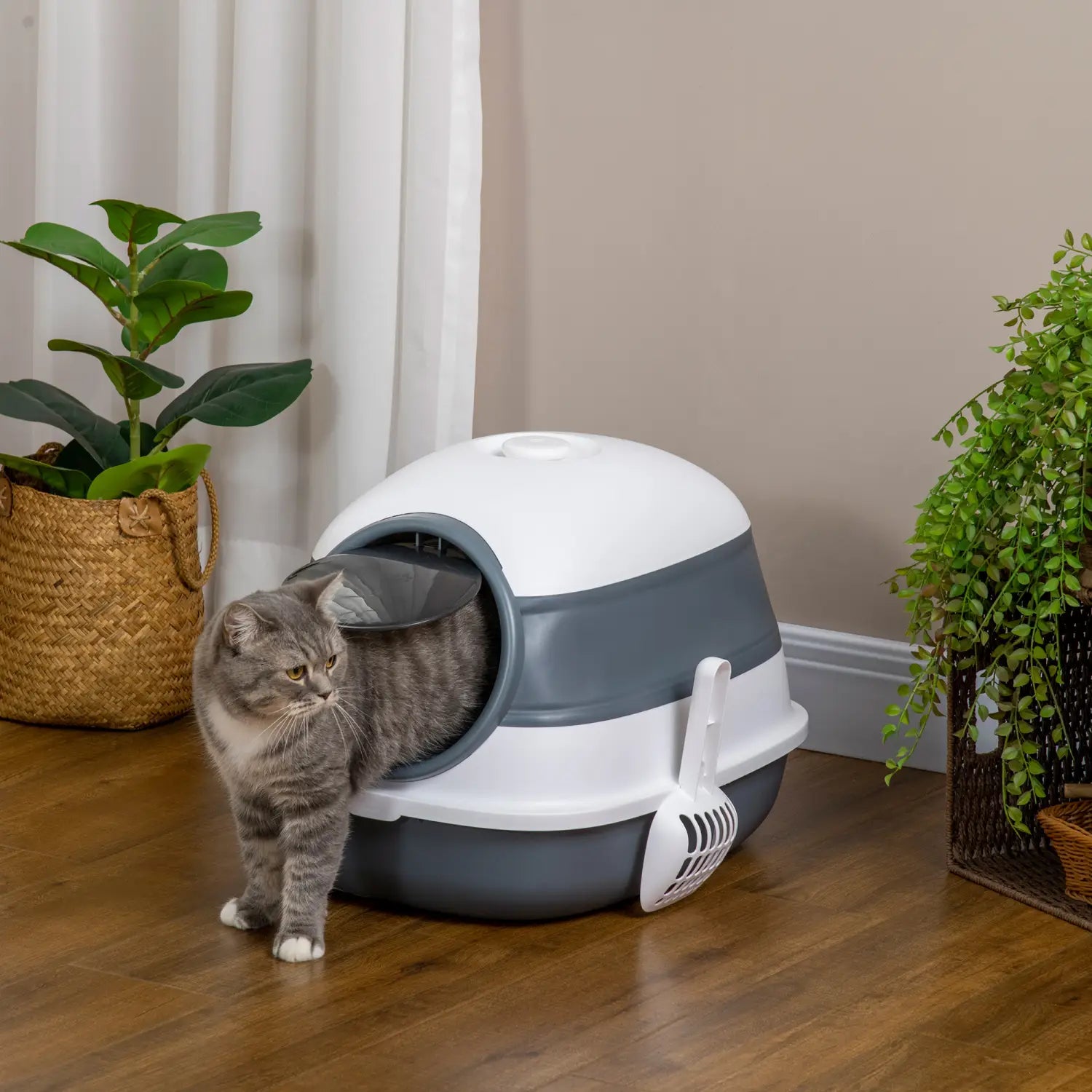Caja para arena de gato con cubierta tipo cúpula en color gris y blanco, con entrada lateral y una pala incorporada para una limpieza conveniente.