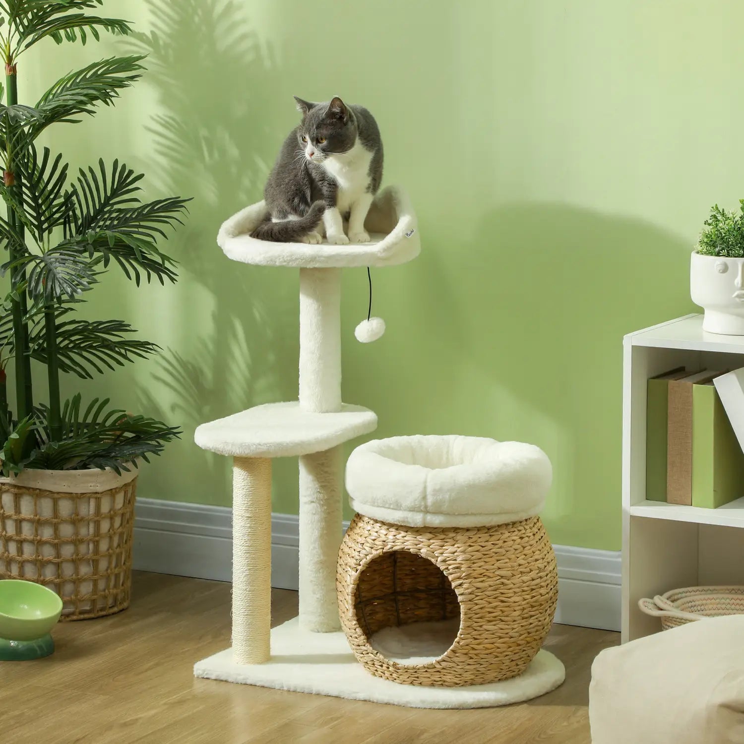 Cream-colored cat tree tower with woven wicker base, plush white platforms, a scratching post, and a cozy hammock-style perch for cats.