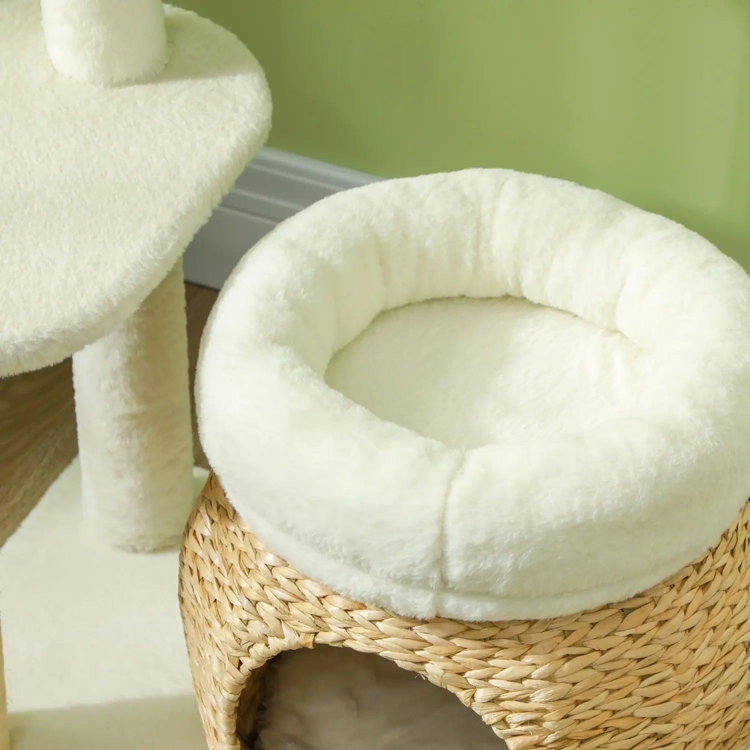 white plush cat bed with a woven wicker base featured on a cat tree tower with scratching posts and beds