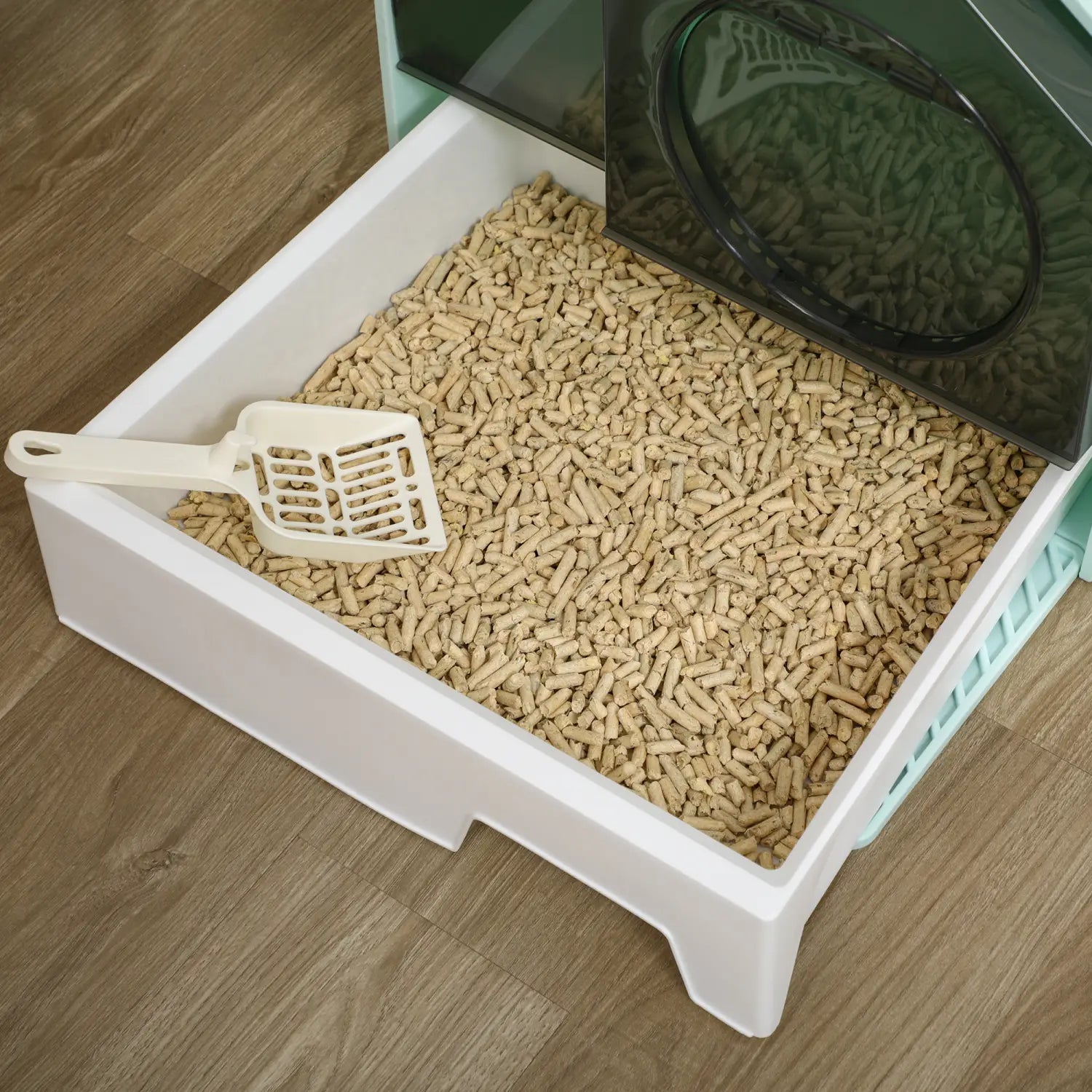 white plastic covered cat litter box filled with beige pellet litter and equipped with a matching scoop and mat for easy cleaning and odor control