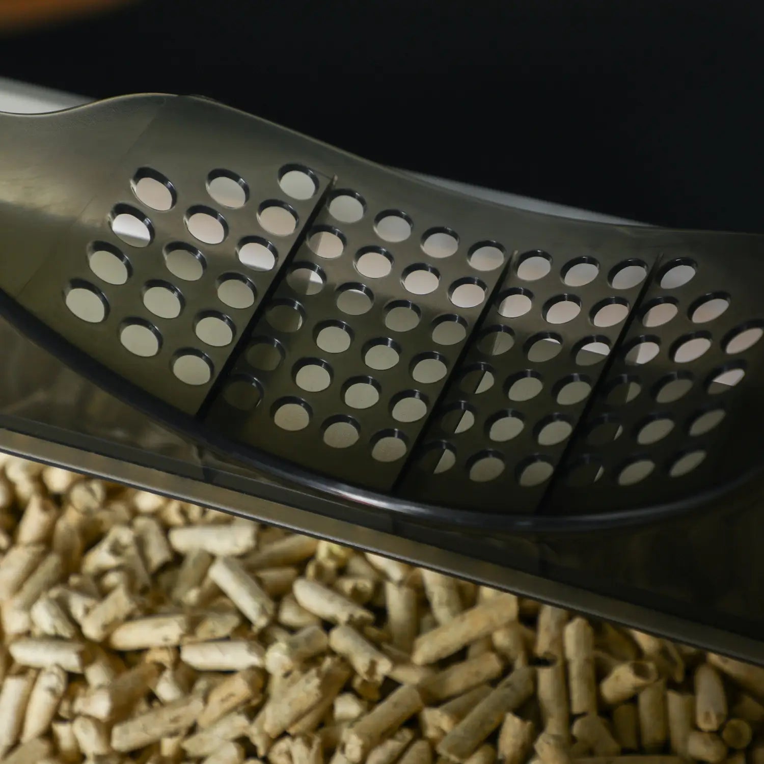 Épandeur de granulés en plastique noir conçu avec des perforations circulaires, destiné à un bac à litière couvert pour chat avec tiroir et tapis.