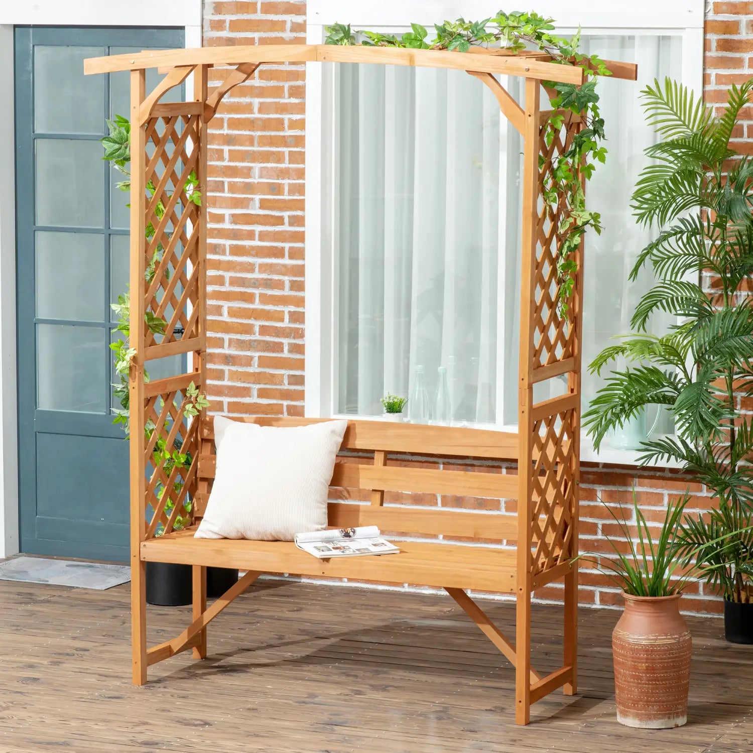Banco de jardín para pérgola de madera color marrón claro, con laterales de celosía y cojín blanco con enrejado y arco de pérgola.