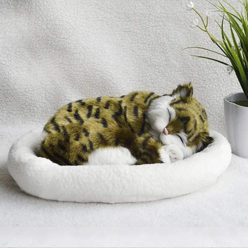 A plush sleeping leopard cat toy with green and black stripes resting in a soft white pet bed as a realistic breathing plush cat figurine with pet bed.