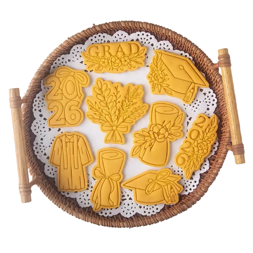 Golden 2026 graduation cookie cutter set features caps gowns diplomas shaped sugar cookies arranged on woven basket