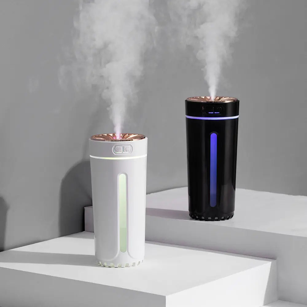 Two sleek cylindrical phantom cup humidifier silent usb air diffusers in white and black with rose gold tops emitting a gentle mist.