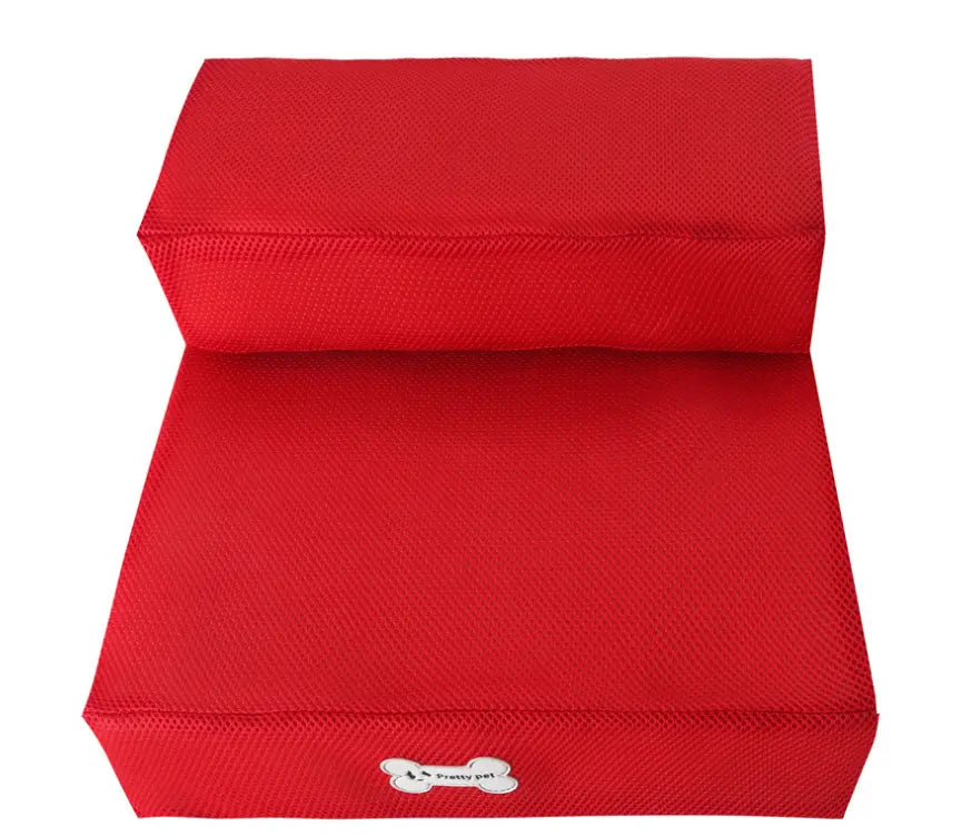 Escalera plegable de malla para mascotas de dos niveles con tapicería de tela texturizada roja y un logotipo blanco con forma de hueso en el escalón inferior.