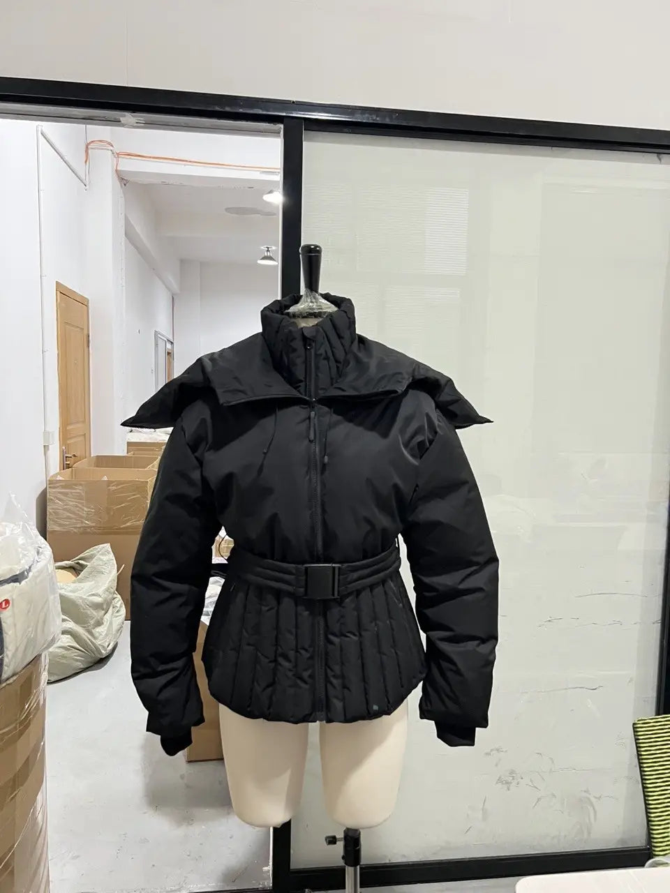 black women’s belted hooded puffer coat with structured wide collar and cinched waist belt designed for cold weather.