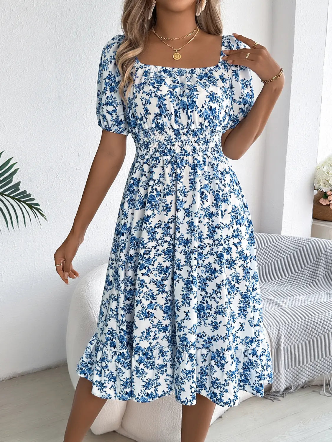 Robe d’été à encolure carrée florale blanche, manches bouffantes à volants, avec un délicat motif floral bleu et manches courtes bouffantes.