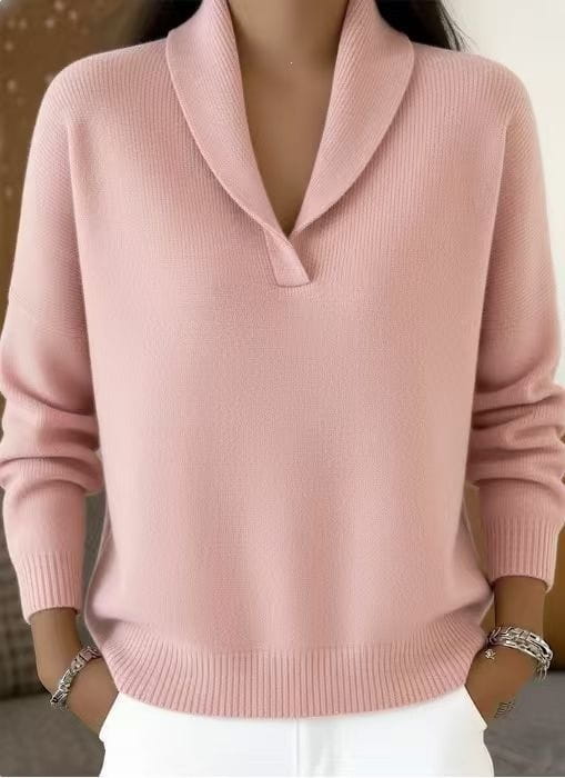 Ein zarter rosafarbener Strickpullover mit langen Ärmeln und V-Ausschnitt, locker geschnitten, mit klassischem Schalkragen und gerippten Bündchen.