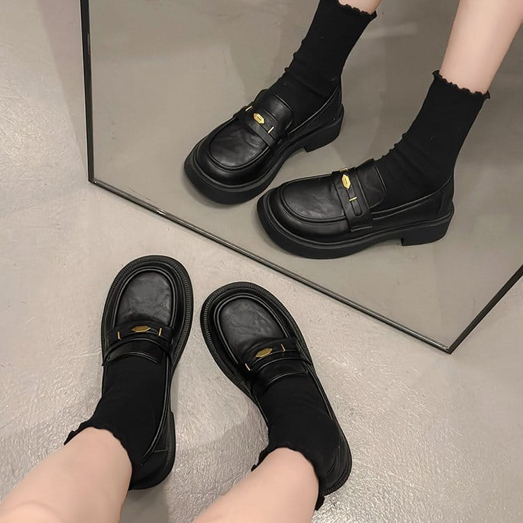 black leather loafers with gold-tone buckle accents and chunky soles showcasing a stylish alternative to brown leather loafers with gold buckle detail