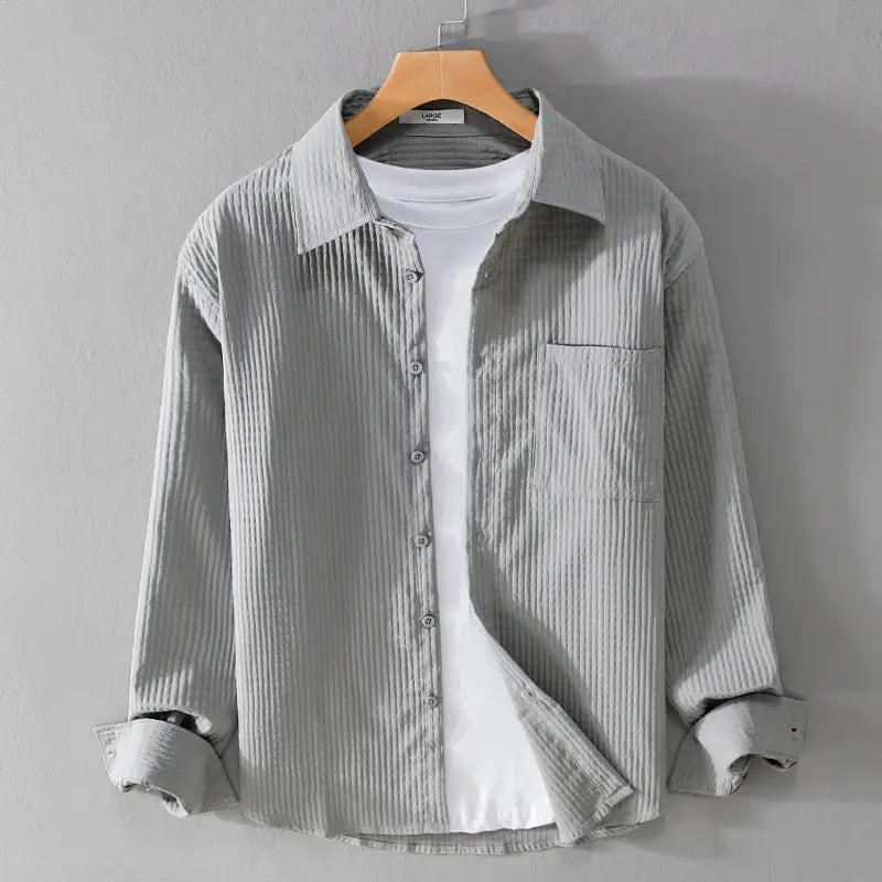Chemise homme décontractée à manches longues en tissu de velours côtelé gris clair, avec un col classique et une poche poitrine.