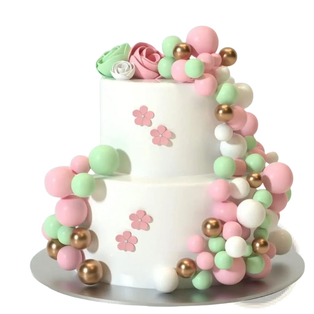 A two-tiered white cake decorated with pink mint green and gold foam balls and delicate pink flower toppers for birthday and wedding decor