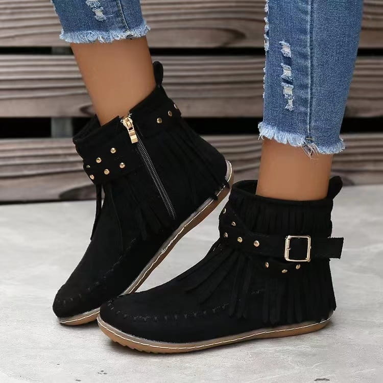 Botines retro negros de ante con flecos, tachuelas metálicas y calzado plano con correa con hebilla.