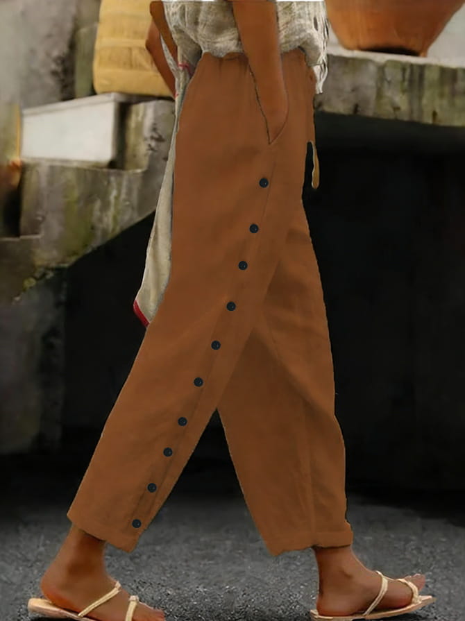 Cropped patchwork button casual pants for women featuring tan linen trousers with a straight-leg cut and dark blue buttons down the side seam.