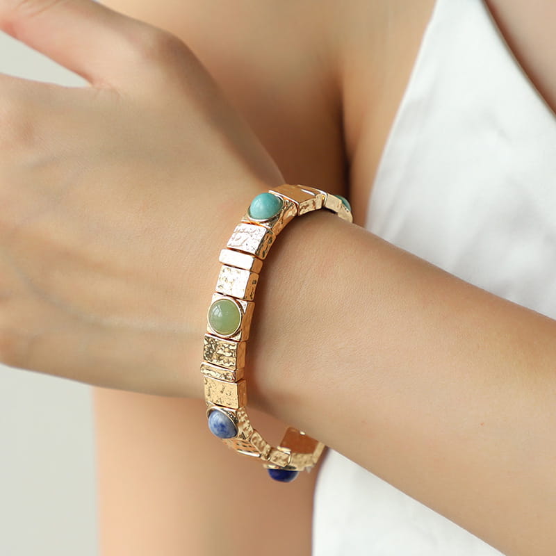 Vintage hammered gold bangle featuring textured rectangular links with alternating turquoise green jade and deep blue gemstones.