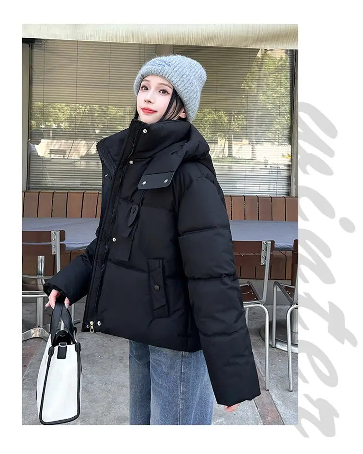 Veste courte matelassée à capuche pour femme noire, avec col haut, fermeture éclair frontale et deux poches latérales, conçue pour l’habillement d’hiver chaud.