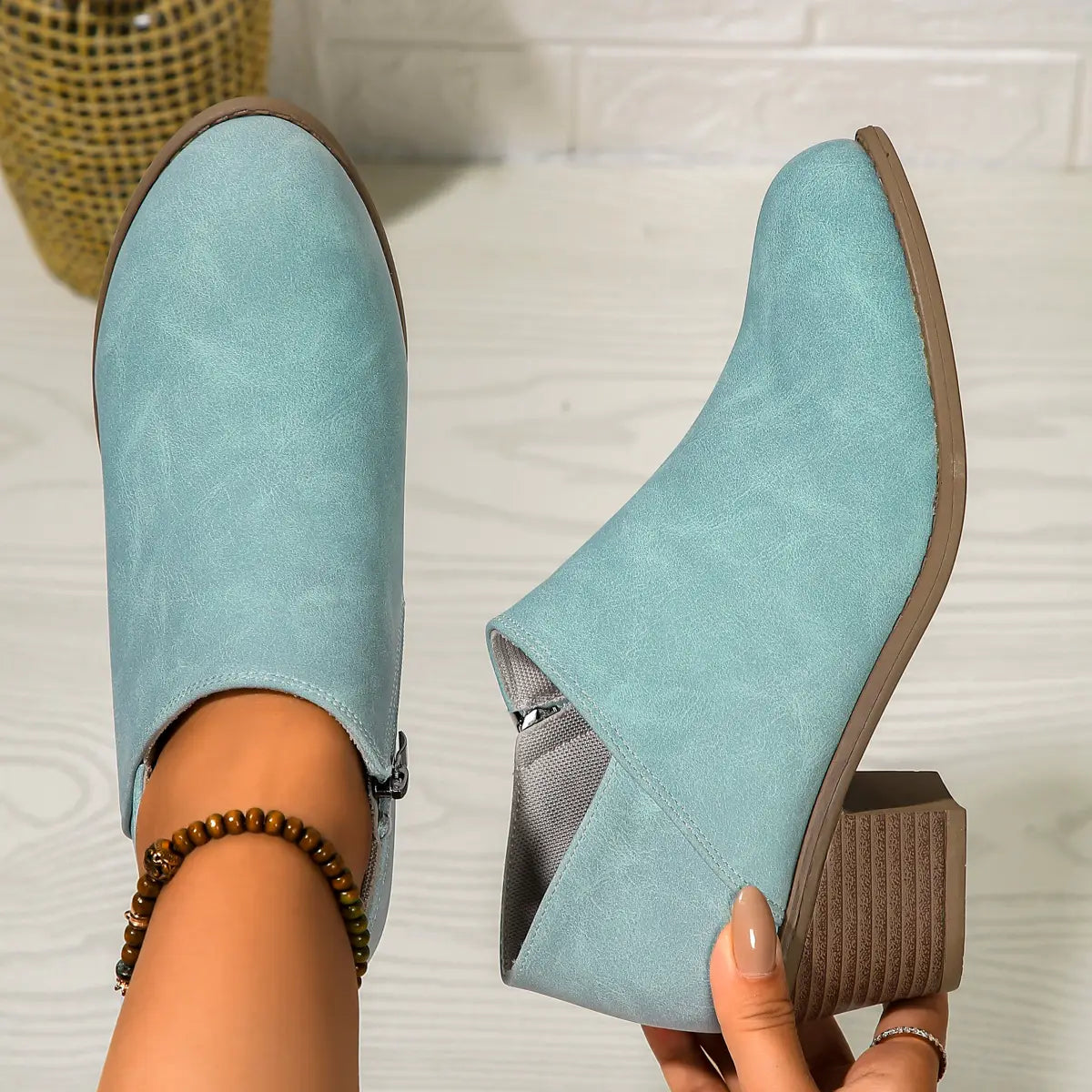 Light blue suede ankle boots with a brown chunky block heel and side zipper closure.
